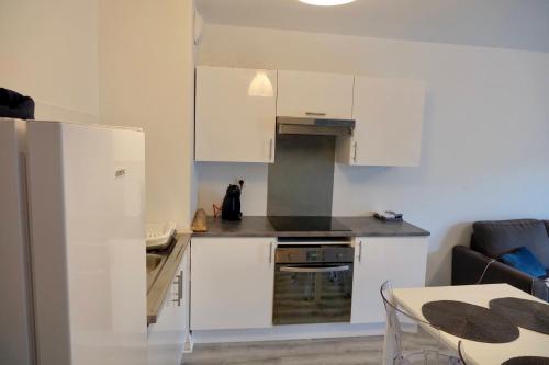 una pequeña cocina con armarios blancos y una mesa en Appartement dans résidence au calme, en Bayona