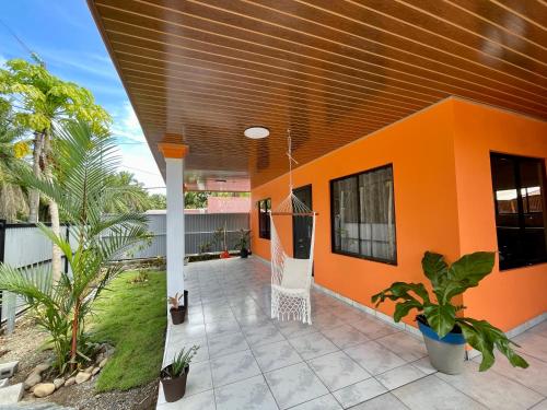 una casa naranja con una silla en el patio en Casa Paraiso Tropical, en Parrita