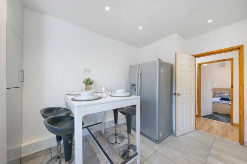a kitchen with a table and two stools and a refrigerator at Faulds Crescent Lodge ✪ Grampian Lettings Ltd in Aberdeen
