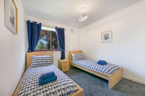 a bedroom with two beds and a window with blue curtains at Faulds Crescent Lodge ✪ Grampian Lettings Ltd in Aberdeen