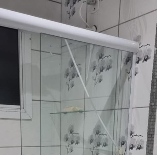 a glass shelf in a bathroom with flowers on the wall at Casa no Moradas in Pelotas