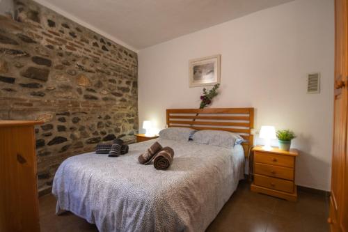 1 dormitorio con cama y pared de piedra en La Casa Del Abuelo, en Vélez-Málaga