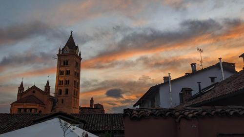a building with a clock tower with a cloudy sky at Loft64 in Alba