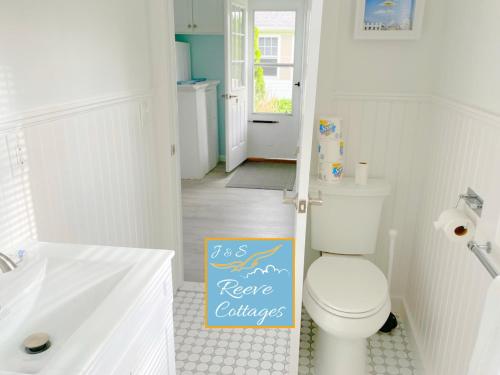 La salle de bains est pourvue de toilettes blanches et d'un panneau au sol. dans l'établissement Premier Waterfront Cottage 1, à Riverhead