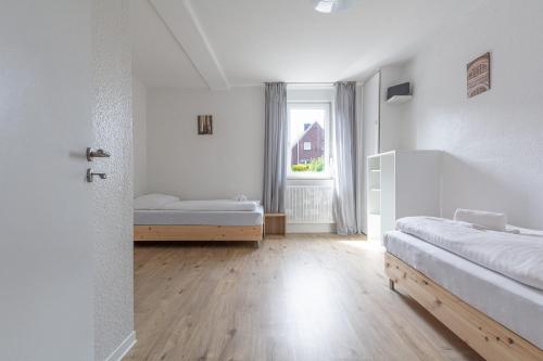 a white room with two beds and a window at T&K Apartments Wegberg 5 Monteur Apartments in Wegberg