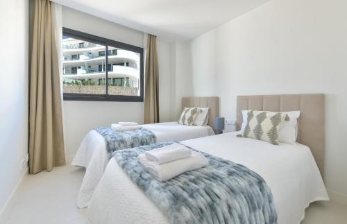 dwa łóżka w pokoju z oknem w obiekcie SolMalaga SeaView Pool & Parking w mieście Fuengirola
