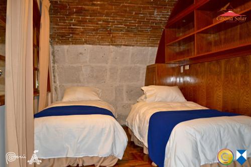 two twin beds in a room with a brick wall at Hotel Casona Solar in Arequipa