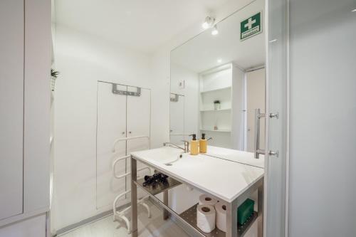 a white bathroom with a sink and a mirror at OPORTO GUEST Moinho de Vento Studios in Porto