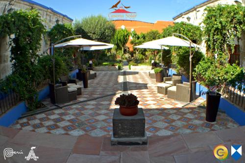 a patio with umbrellas and chairs and plants at Hotel Casona Solar in Arequipa
