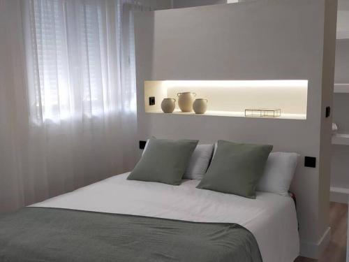 1 dormitorio con cama blanca con almohadas y estante en Ospede Luscofusco Carballo-Costa da Morte, en Carballo