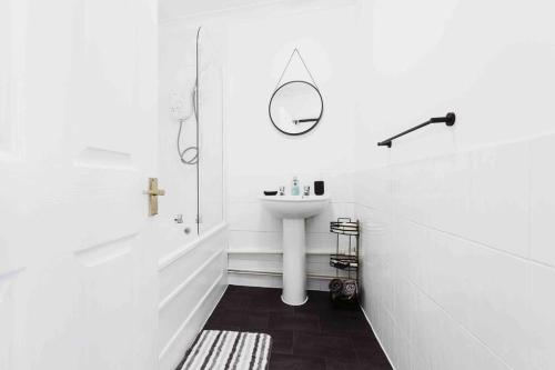 a white bathroom with a sink and a mirror at The Minimalist - Entire 1 bed flat near Gunwharf Quays, Ground Floor Flat Private Entrance in Portsmouth