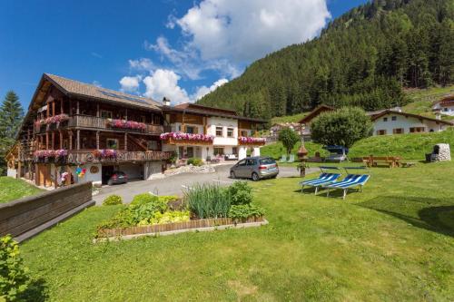 Un edificio con sillones azules en el césped. en B&B Ciauceia, en Selva di Val Gardena