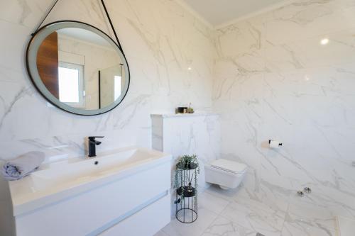 a bathroom with a sink and a mirror and a toilet at Holiday home Carpinus in Široki Brijeg