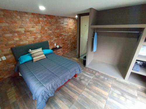 ein Schlafzimmer mit einem Bett und einer Ziegelwand in der Unterkunft R09 LUXURY STUDIO POWER a 5 MIN DEL ITESM R09 in Mexiko-Stadt