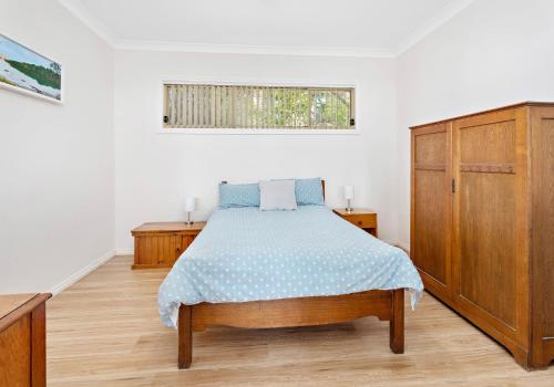 a bedroom with a bed and a wooden cabinet at Cosy cottage by the sea in Gerroa