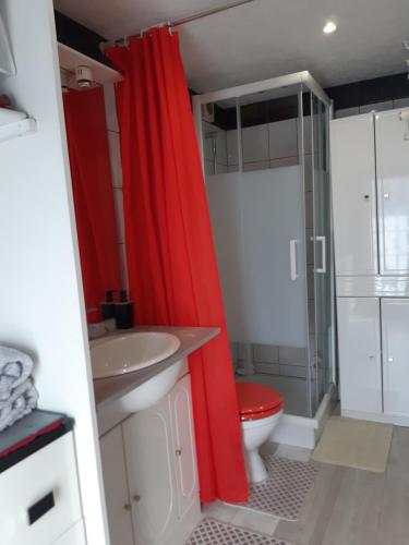La salle de bains est pourvue d'un rideau de douche rouge et de toilettes. dans l'établissement Studio indépendant, à Saint-Illiers-la-Ville