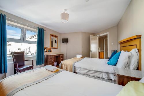 1 dormitorio con 2 camas, silla y ventana en Iona Inn, en Derry Londonderry