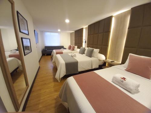 a hotel room with two beds and a mirror at HOTEL SANTORI in Pasto