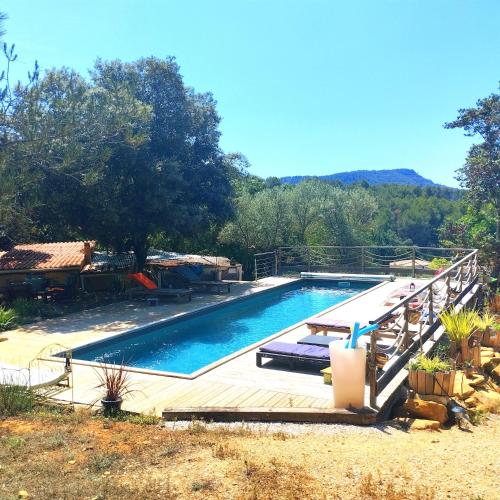 une grande piscine avec une terrasse en bois à côté de celle-ci dans l'établissement Arche de Noé atypique, bohème , nature, piscine chauffée de Pâques à Toussaint , spa , sauna , loisirs, au Beausset