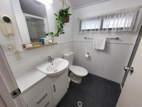 a white bathroom with a toilet and a sink at Ellis Beach Oceanfront Holiday Park in Palm Cove