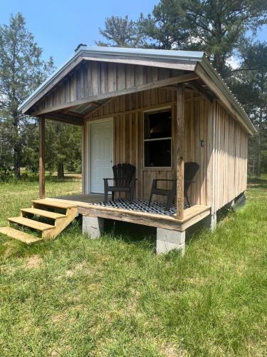 Cette petite cabane en bois dispose d'une terrasse couverte et de 2 chaises. dans l'établissement Grizzly Ranch, à Geneva