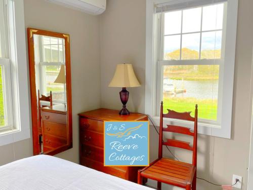 - une chambre avec un lit, une chaise et une commode dans l'établissement Premier Waterfront Cottage 2, à Riverhead