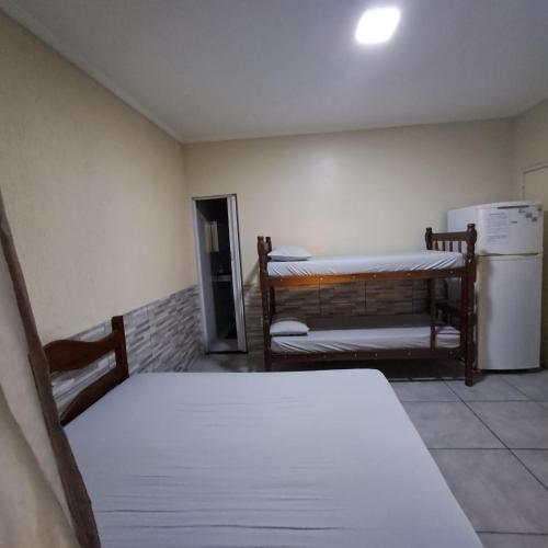 Habitación con 2 camas, mesa y nevera. en Suíte Caminho do Sol, en Arraial do Cabo