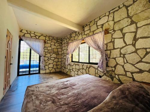 1 dormitorio con 1 cama grande en una pared de piedra en Finca Bermúdez - Cabaña del Rio, en Huasca de Ocampo