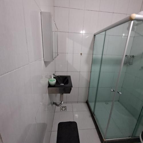 Un baño con lavabo y ducha de cristal. en Suíte Caminho do Sol, en Arraial do Cabo