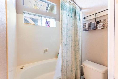 uma casa de banho com uma banheira, um WC e uma cortina de chuveiro. em Cozy Home in the Heart of Elk Grove em Elk Grove