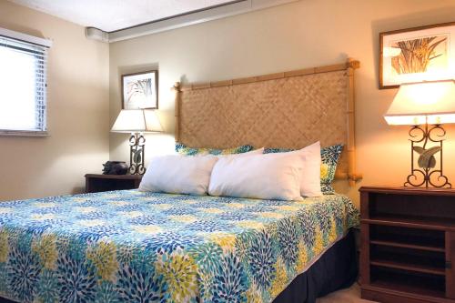 ein Schlafzimmer mit einem Bett mit einer blauen und gelben Tagesdecke in der Unterkunft Kuhio Shores 416 in Koloa