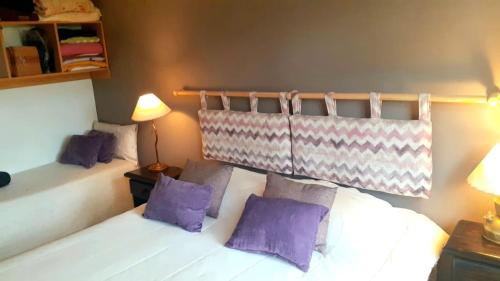 - une chambre avec un lit blanc et des oreillers violets dans l'établissement Kaulemu, à San Carlos de Bariloche