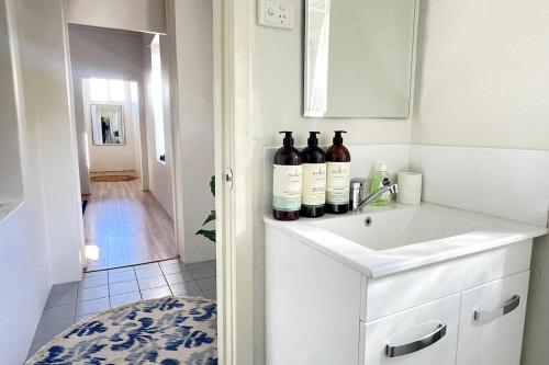 a bathroom with bottles of wine on a sink at Rosa's Place 4 South Beach Charm in South Fremantle