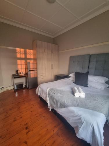 1 dormitorio con 2 camas y suelo de madera en Capital On French Guest House, en Pietermaritzburg