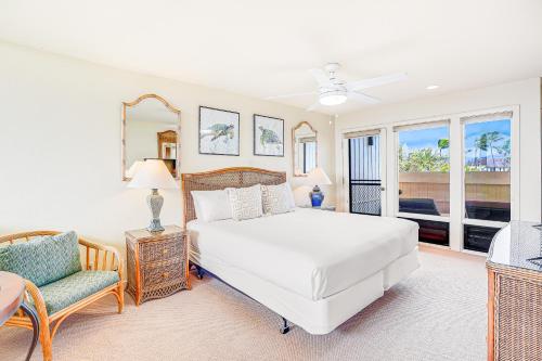 a white bedroom with a bed and a chair at Manualoha 608 in Koloa