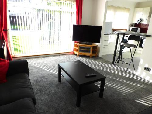 a living room with a couch and a tv and a table at Charming 2 bed house Perfect base for sightseeing in Johnstone
