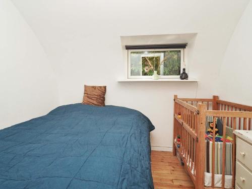 Un dormitorio con una cama azul y una ventana en Holiday home Frederiksværk XXIV, en Frederiksværk
