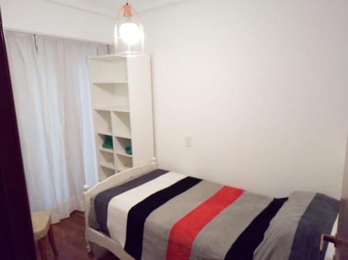 1 dormitorio con 1 cama con manta a rayas en Depto impecable en La Perla Mar del Plata en Mar del Plata