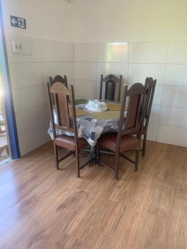 a dining room table with four chairs and a table at Pousada GigiRetrô Catas Altas-MG in Catas Altas