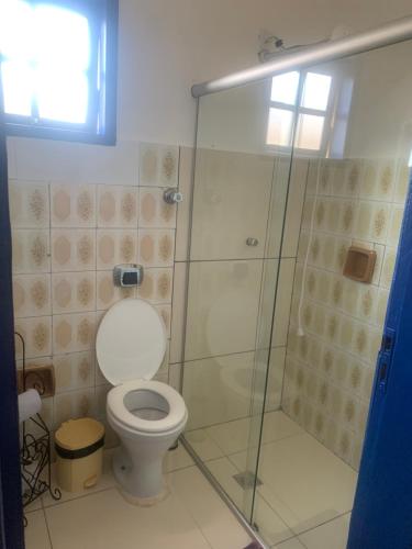 a bathroom with a toilet and a glass shower at Pousada GigiRetrô Catas Altas-MG in Catas Altas