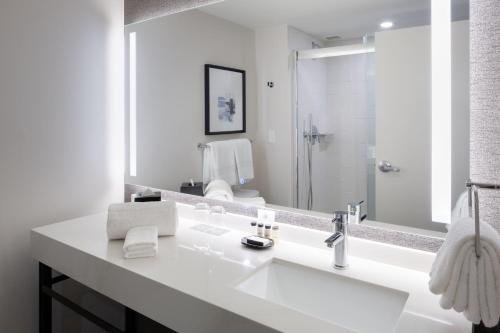 Baño blanco con lavabo y espejo en Sheraton Hartford Hotel at Bradley Airport en Windsor Locks