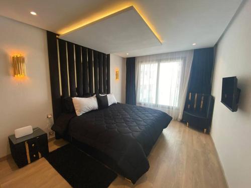 a bedroom with a large black bed and a window at Corniche Casablanca - Black New in Casablanca