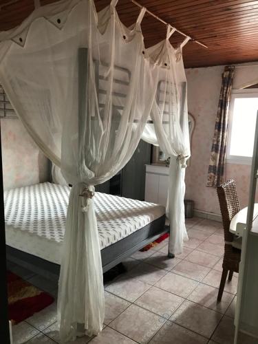 1 dormitorio con cama con dosel y cortinas blancas en Le coin tranquille en Le Lamentin