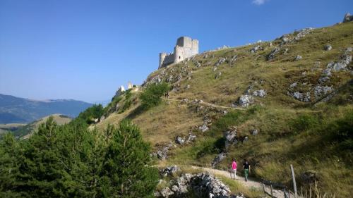 a group of people walking up a hill with a castle at Casa Hemingway - Casa Vacanze in Barisciano