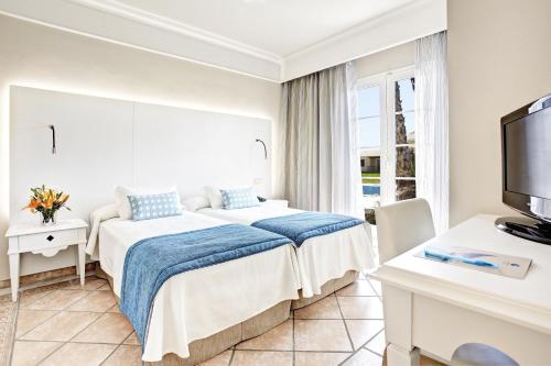 a hotel room with two beds and a television at Grupotel Playa Club in Son Xoriguer