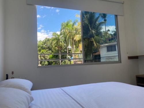 a bedroom with a window with a view of palm trees at Casa Hawai in Melgar