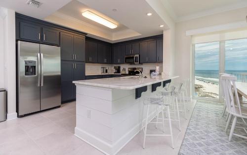 eine Küche mit Kühlschrank und Theke mit Hockern in der Unterkunft Phoenix Gulf Tower 1004 condo in Gulf Shores