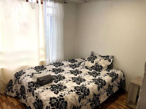 a bedroom with a black and white bed and a window at Hermosa Cabaña Campestre Puente Boyacá in Ventaquemada