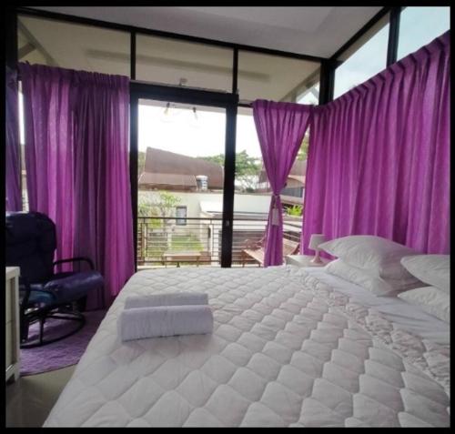 a large white bed in a bedroom with purple curtains at Vimala Hills FARLA Villa - 3BR in Gadok 1