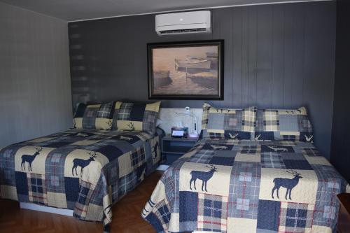 a bedroom with two beds and a picture on the wall at Motel de L'Anse et Camping Rimouski in Rimouski